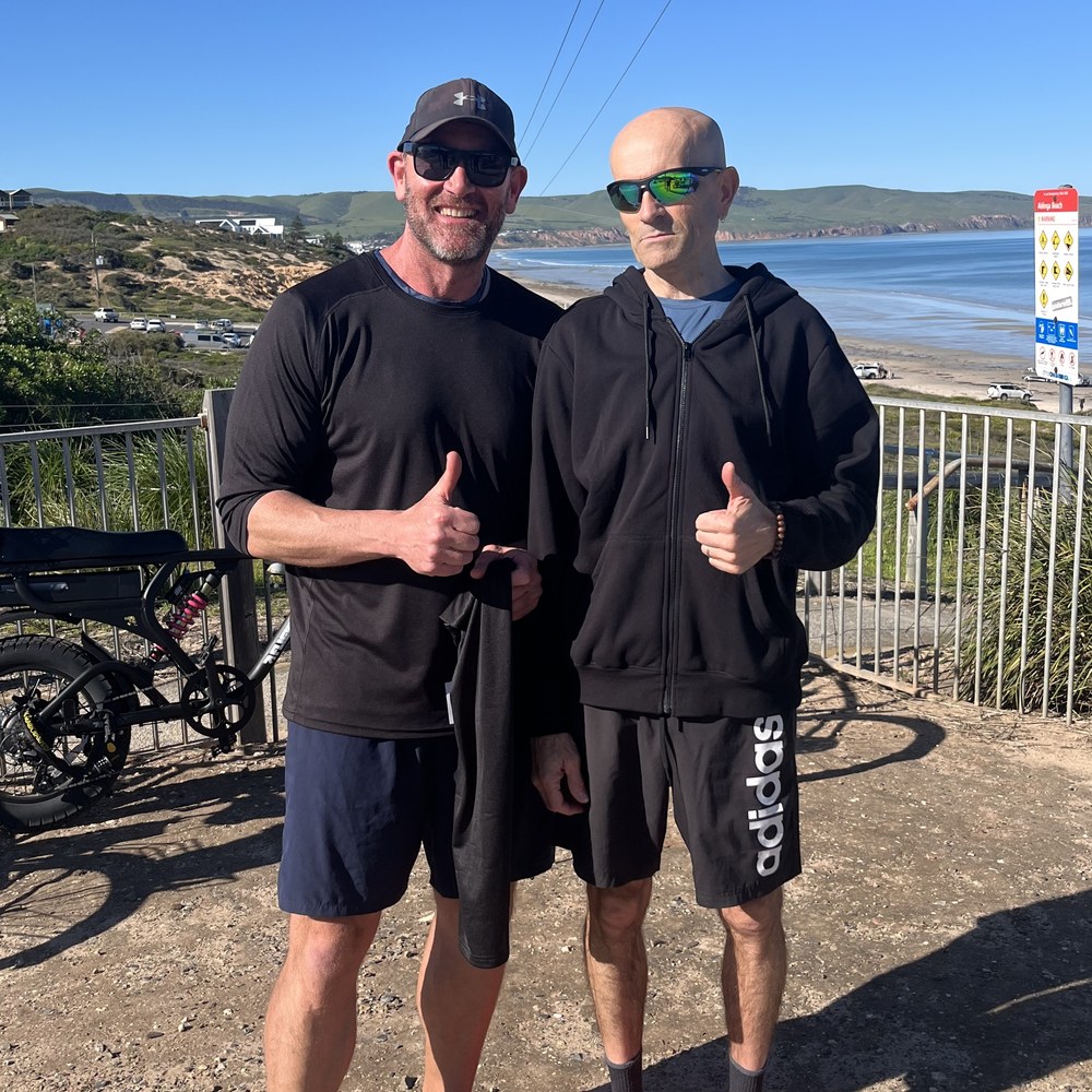 Two people in NxsTech Performance kit at Aldinga Beach, giving a thumbs up.