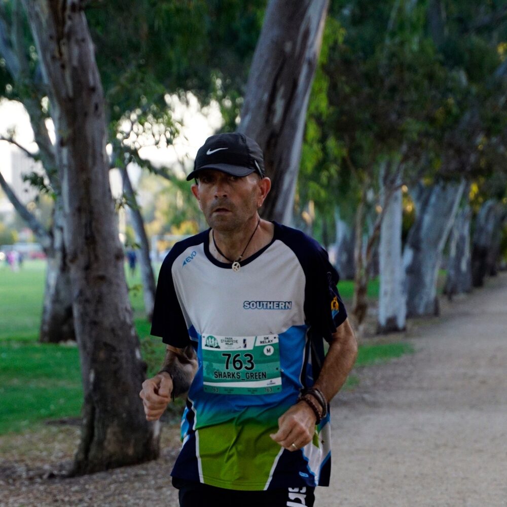 Simon mid-race on a tree-lined path in club colours.